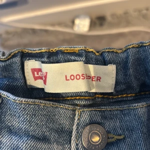 Levi's ljusblå loose fit jeans - Ljusblå jeans från Levi's i loose fit-modell med klassisk femficksdesign och gul kontrastsöm. Jeansen har raka ben och är tillverkade i slitstarkt denimtyg. Perfekta för en avslappnad och trendig look.