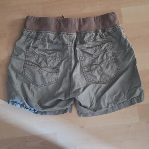 Gröna shorts med snörning - Snygga och sköna shorts med jättefina detaljer på bakfickorna och rymliga framfickor. Ribbad midja gör att de passar 36-38, kanske 40