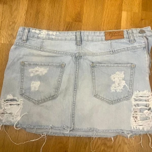 Ljusblå lågmidjad jeanskjol - Ljusblå lågmidjad jeanskjol med slitna detaljer från Perfect Jeans. dragkjedan sitter på sidan av kjolen🩷midjemåttet är 39 rakt över och den är 30 cm lång