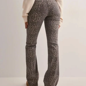 Leopardmönstrade bootcut jeans - Snygga jeans med leopardmönster i grå och beige toner. Byxorna har bootcut-modell och hög midja, vilket ger en trendig och smickrande siluett. Perfekta för dig som vill sticka ut med ett coolt mönster och bekväm passform.