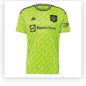 Manchester United neon gul matchtröja - Säljer en neon gul Manchester United fotbollströja från Adidas med svarta detaljer och klubbmärke på bröstet. Tröjan har korta ärmar, rund hals med mönstrad kant och tryckta sponsorer. Perfekt för dig som vill sticka ut på planen. Tryckt med Elanga i bak🕺