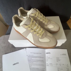 Maison Margiela GATS - Margiela sneakers i beige och vitt med klassisk gummisula. Ovandel i mocka och skinn, snygga kontraster mellan material och färger. Låga med rund tå och snörning. Perfekta för dig som gillar stilrena och trendiga sneakers. Box ingår tyvärr inte men allt annat medkommer! 