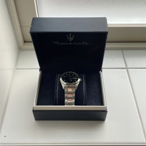 Maserati herrklocka i rostfritt stål - Stilren Maserati herrklocka med blå urtavla och datumvisning. Klockan har ett klassiskt armband i silverfärgat rostfritt stål och levereras i originalbox. Snyggt Maserati-logo på både urtavla och spänne. Perfekt accessoar för dig som gillar italiensk design. Bara använd 2 gånger.