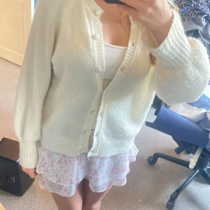 Rosa blommig volangkjol från Gina Tricot - Supersöt kort volangkjol från Gina Tricot i vitt med rosa blommigt mönster. Kjolen har elastisk midja och flera lager volanger som ger en flowy och luftig känsla. Perfekt för sommarens alla tillfällen när du vill känna dig extra söt och bekväm. Är i barnstorlek men som sagt elastisk midja så passar nog upp till M!💕