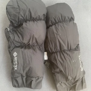 Svarta GORE-TEX-vantar från Hestra/Snowsport - Riktigt varma svarta tumvantar från Hestra med GORE-TEX Infinium-yttertyg och slät skinninsida för extra grepp. Vantarna har elastiska muddar och justerbart spänne vid handleden. Perfekta för kalla vinterdagar och snöaktiviteter.