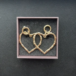 Guldiga hjärtformade örhängen - Säljer ett par stora örhängen i guldmetall med cool bambuliknande struktur. De är formade som hjärtan och har en chunky ring upptill som fäste. Perfekta för dig som vill sticka ut med ett statement-smycke!
