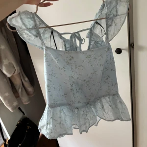 Ljusblå blommig blus med volang - Supersöt ljusblå blus med blommigt mönster