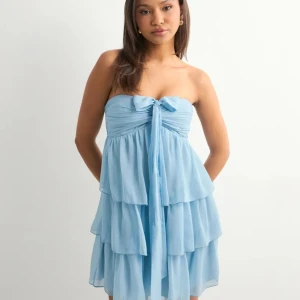 Ljusblå volangklänning med rosett - Supersöt ljusblå kortklänning med flera volanger och en stor rosett framtill. Klänningen har avtagbara axelband som kan knytas på olika sätt och smock i ryggen för extra komfort. Perfekt för sommarens alla tillfällen! Köpt för 500 kr. I nytt skick! Använd fåtal gånger. Pris kan diskuteras 