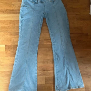 Ljusblå bootcut jeans med Y2K stil (låg midja) - Säljer nu mina snygga ljusblå jeans med bootcut och låg midja. Jag köpte dom för 700 kr och säljer dom nu för 400kr. Och jag har använt dom 1 gång så dom är i princip helt nya.(Priset kan diskuteras) Jeansen har breda bälteshällor och markerade sömmar framtill för en snygg retrovibe. Perfekta om du gillar 00-talsstilen och vill ha ett par jeans som sticker ut lite extra.
