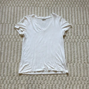 Vit t-shirt med v-ringning - Vit basic t-shirt med v-ringning och korta ärmar. Tillverkad i mjuk bomull, perfekt för en clean och enkel stil. Passformen är normal och tyget är tunt och skönt mot huden🩷