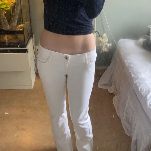 Vita jeansbyxor från Gina Tricot - Säljer ett par vita jeansbyxor från Gina Tricot med låg midja och raka ben. Byxorna har klassiska fickor fram och bak, samt snygga detaljer på bakfickorna. Perfekta för dig som gillar en clean och fräsch look.
