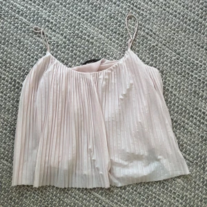 Plisserad ljusrosa linnetopp från Zara - Supersöt ljusrosa linnetopp från Zara Trafaluc med tunna axelband och plisserat tyg. Toppen är luftig och har en flowy passform som känns riktigt fräsch till sommaren. Perfekt att styla med jeans eller kjol för en chill look.