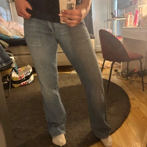 Blå bootcut jeans med låg midja - Säljer ett par klassiska blå jeans med bootcut och låg midja. Jeansen har en lätt tvättad look, fem fickor och stängs med dragkedja och knapp. Perfekta för dig som gillar en avslappnad och tidlös stil.