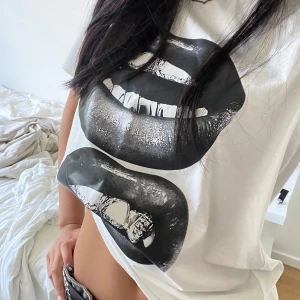 Vit t-shirt med svart läppar-print - Säljer en vit t-shirt med två stora svarta läppar-prints framtill. Står att den är i storlek M men skulle säga att den passar S bättre.