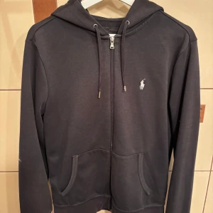 Ralph Lauren zip-hoodie - Tjena, säljer denna feta zip hoodien från Ralph Lauren. Sparsamt använd och väldigt bra skick. Ända skavanken är den lilla skadan som skett i slutet på 1 av snörena samt små saker som sker som vanligt vid användning, också därför den säljs så billigt. Köpt för ett tag sedan för 1,500kr! Väljer du att betala direkt via Swish kan jag gå ner lite i pris eftersom vi då slipper all väntetid som tillkommer via betalning genom Plick!🏆 Skicka ett PM vid frågor eller funderingar.