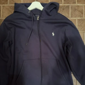 Ralph Lauren zip-hoodie - Säljer denna feta Ralph Lauren zip-hoodien i extremt bra skick. Endast legat i garderoben och köpt för ett par månader sedan för 1,500kr! Väljer du att betala direkt via Swish kan jag gå ner lite i pris eftersom vi då slipper all väntetid som tillkommer via betalning genom Plick!🏆 Skicka ett PM vid frågor eller funderingar.