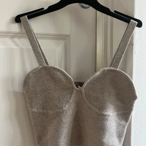 Beige stickad korsettopp H&M S - Superfin beige stickad korsettopp från H&M i storlek S. Toppen har breda axelband och markerade kupor för en snygg siluett. Mjuk och stretchig stickad kvalitet som känns skön mot huden. Perfekt att styla med jeans eller kjol för en trendig look.