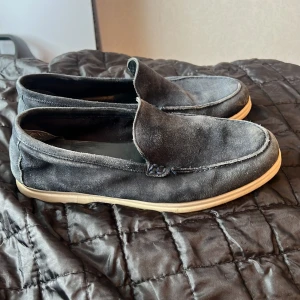 Mörkblå mockaloafers från T. Watson - Snygga loafers i mörkblå mocka från T. Watson med ljus, platt sula. Skorna har en klassisk, stilren design med rund tå och diskreta sömmar. Perfekta för dig som gillar en avslappnad men ändå dressad look.