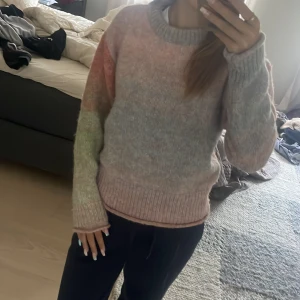 Pastellfärgad stickad tröja från ONLY - Supermysig stickad tröja från ONLY i pastelliga toner av rosa, lila, grön och blå. Tröjan har en loose fit, ribbade muddar och rund halsringning. Perfekt för dig som gillar en chill och färgglad vibe.