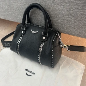 Svart handväska Zadig & Voltaire skinn - Säljer min Sunny XS Studs som bara använts försiktigt. Den är i väldigt bra skick, köpt för 2650 kr via Plick. Jag har börjat använda en annan väska mer, så denna får lämna samlingen. Mått: 23 x 14 x 11.5 cm. 