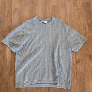 Ljusgrå mesh t-shirt från Bershka - Säljer en ljusgrå t-shirt från Bershka i meshmaterial med snyggt hålmönster över hela tröjan. T-shirten har rund halsringning, korta ärmar och relaxed fit. 