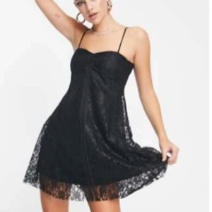 Svart spetsklänning med tunna axelband - Supersöt svart kort klänning med tunna axelband och spetsdetaljer. Klänningen har en lätt utsvängd form och är perfekt för dig som gillar en feminin och trendig look. Spetsen ger en extra touch och den är ärmlös för en luftig känsla.