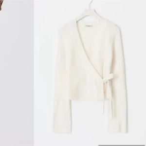 Vit omlottkofta från gina - Superfin vit omlottkofta från gina tricot  med knyt i sidan. Koftan är stickad och har lång ärm, v-ringning och en mjuk, fluffig känsla. Perfekt att slänga över ett linne eller t-shirt för en chill look.