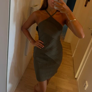 Olivgrön kort klänning från NLY One - Snygg olivgrön kort klänning med korsade axelband och öppen rygg. Tight passform med ett tyg som sitter väldigt smickrande. Klänningen är ny med prislapp.