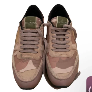 Valentino Garavani camo sneakers - Snygga sneakers från Valentino Garavani i beige och bruna toner med camouflage-mönster. Skorna har snörning, rund tå och är tillverkade i en mix av mocka och skinn. Perfekta för dig som vill sticka ut med en exklusiv streetstyle.
