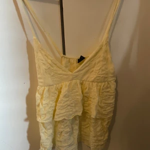 Gul volangtop från Gina Tricot - Supersöt ljusgul linnetopp från Gina Tricot med volanger och smala axelband. Kommer inte till användning då jag inte riktigt passa i den tyvärr😤😤