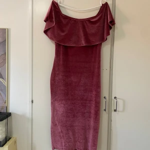 Rosa sammetsklänning offshoulder - Snygg medellång rosa event klänning. Med offshoulder och bred volang upptill. Klänningen har en figurnära passform och är perfekt för dig som vill sticka ut med en elegant och trendig look. Jag står inte för retur eller för postens slarv.