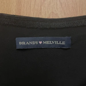 Svart mesh-linnetopp Brandy Melville - Svart ärmlös linne-topp från Brandy Melville i tunn, transparent mesh. Modellen är figurnära med vågig kant nertill och rund halsringning. Perfekt att styla lager på lager eller med coola accessoarer.