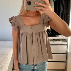 Topp med knappar - Supersöt grå topp med knappar ifrån Zara! Inga defekter! Storlek xs men passar även S! På semester nu! Men kan resvera plagg ist! Så bara att skriva så reserverar jag💞💞SKRIV INNAN NI KÖPER SÅ PLAGGET FINNS