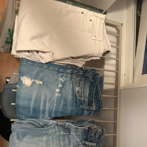 Tre par jeans i olika färger - Säljer tre par jeans: ett par vita jeans med klassisk femficksdesign, ett par ljusblå slitna jeans med trasiga detaljer och ett par ljusblå jeans med tvättad look. Perfekta för dig som gillar en avslappnad och trendig stil. Första paret är från märket Lee 33/34   Andra paret är G-star 28/32   Tredje paret är märker zatiny med storlek 32/32  Kom med bud för snabb affär 
