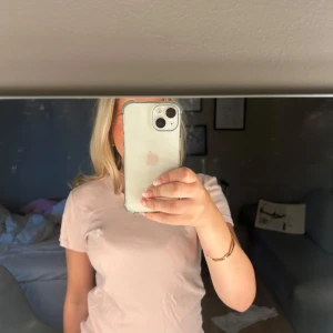 Ljusrosa t-shirt från Ralph Lauren - Supersöt ljusrosa t-shirt från Ralph Lauren i 100% bomull. Klassisk passform med korta ärmar och rund halsringning. Diskret broderad logga på bröstet. Perfekt till jeans eller shorts för en clean och fräsch look. Tröjan har en liten fläck som man kan se på sista bilden, den tänker man inte på medans man har på sig tröjan dock.