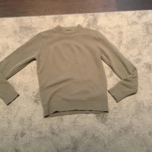 Beige stickad tröja med rund hals - En stilren beige stickad tröja med rund halsringning och långa ärmar. Perfekt för lager-på-lager och passar till både jeans och kjol. Tröjan har ribbade muddar vid ärmslut och nederkant för en snygg passform.