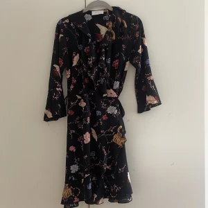 Omlottklänning från Neo Noir - Omlottklänning i ett tunnare material från Neo Noir! Klänningen har trekvartslånga ärmar och volanger samt ett så coolt print! Man knyter åt den själv så storleken går att anpassa lite