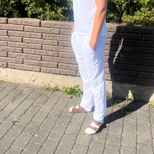 Vita linnebyxor med snörning - Säljer ett par fräscha vita linnebyxor med snörning i midjan och raka ben. Byxorna har sidfickor och en bakficka, perfekt till sommaren. Killen på bilden är 182 cm 