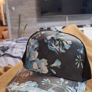 Blommig gg keps  - Snygg gg keps för sommaren svart med blåa blommor som gör dig se mer unik ut