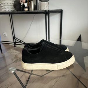 Eytys doja - Stilrena svarta slip-on sneakers från Eytys i mjuk mocka med chunky vit sula. Skorna har en minimalistisk design utan snörning och en rund tå. Perfekta för dig som gillar en clean och modern look.