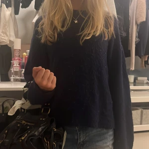 Mörkblå stickad tröja - Mysig mörkblå stickad tröja med lång ärm och klassisk rund hals. Tröjan har en enkel och clean look som passar perfekt till jeans. Den är lite loose i passformen och känns superbekväm att ha på sig.