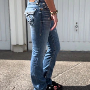 Lågmidjade bootcut jeans - Blå jeans med slitningar. Innerbenslängd: 87cm, midja: 38cm💙 personen på bilden är ca 180cm