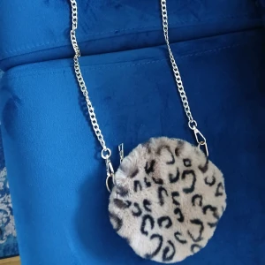 Rund axelväska med leopardmönster - Säljer en rund axelväska med fluffig päls och leopardmönster🐆Väskan har en silvrig kedja som axelrem och är perfekt för dig som vill sticka ut med en cool accessoar😉 Beige och svart färgkombination😍