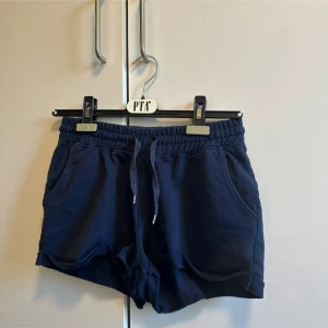 Mörkblå shorts Iconic Sports XS - Mörkblå mjuka shorts från Iconic Sports i storlek XS. De har elastisk midja med snörning, två sidofickor och en avslappnad passform. 