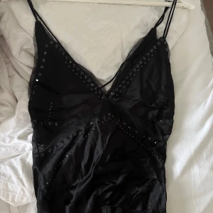 Svart topp med nitar från Zara - Supersnygg svart topp från Zara med tunna axelband och v-ringning. Toppen  har coola nitar och meshdetaljer som ger en edgy vibe. Perfekt för dig som vill sticka ut med en stilren men ändå unik look.