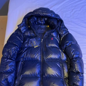 Polo Ralph Lauren Jacka - Säljer en mörkblå dunjacka från Polo Ralph Lauren i storlek S, endast använd en vinter. Nypris 6000 kr, mitt pris 3500! Köpt på NLY MAN, kvitto finns. Mycket bra skick förutom en liten defekt på ryggen, se bild 5. Inget som syns på långt håll. För mer frågor och bilder, skriv privat.