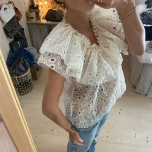 Vit broderad blus med volang  - Superfin vit blus från Wera med broderade hålmönster och stora volanger runt v-ringningen. Helt ny💞