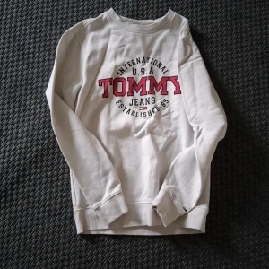 Vit sweatshirt Tommy Jeans S - Vit sweatshirt från Tommy Jeans med stort rött och svart tryck på bröstet. Klassisk crewneck med ribbade muddar och liten broderad logga på ärmen. Regular fit och tillverkad i mjuk bomull. Perfekt för en chill och stilren look. Pris går att diskuteras. 
