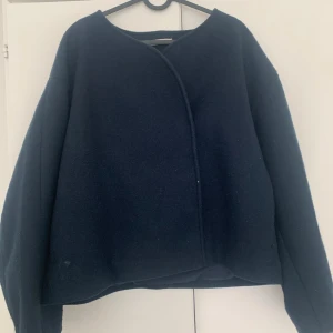 Mörkblå skepparkavaj från Gina Tricot - Säljer en stilren mörkblå skepparkavaj från Gina Tricot. Jackan har dubbelknäppning med svarta knappar, rundad halsringning och är tillverkad i ullblandning. Perfekt för dig som gillar en klassisk och clean look.