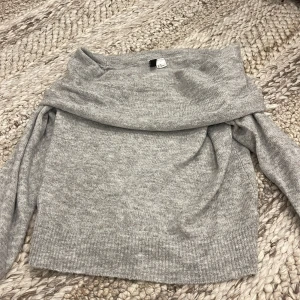 Grå offshoulder stickad tröja H&M - Superfin ljusgrå stickad tröja från H&M Divided i offshoulder-modell. Mjuk och skön med lång ärm och ribbade detaljer vid nederkant och ärmslut. 